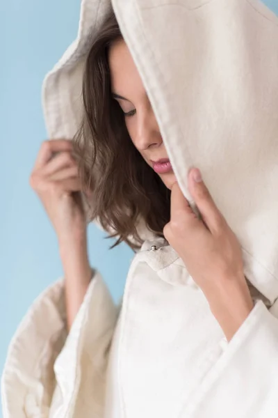 Žena v bílém plášti s kapucí izolované na modrém pozadí — Stock fotografie