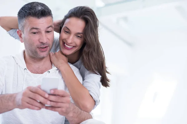 Glückliches Paar nutzt Handy zu Hause — Stockfoto