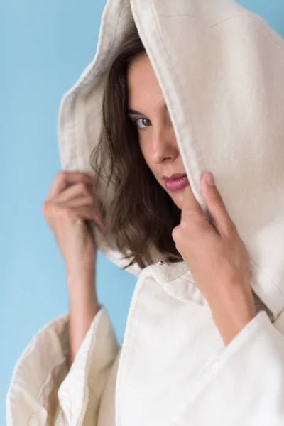 Mulher em um casaco branco com capuz isolado no fundo azul — Fotografia de Stock