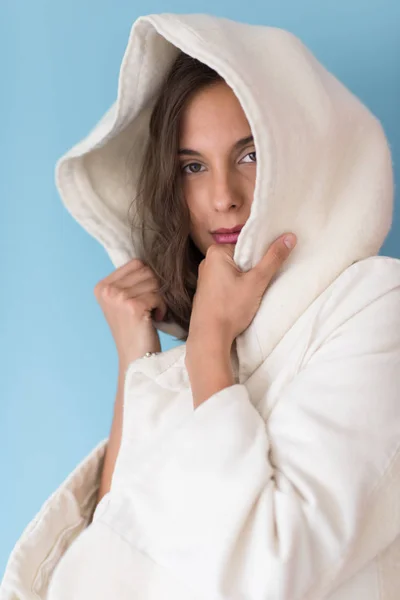 Frau in weißem Mantel mit Kapuze auf blauem Hintergrund — Stockfoto