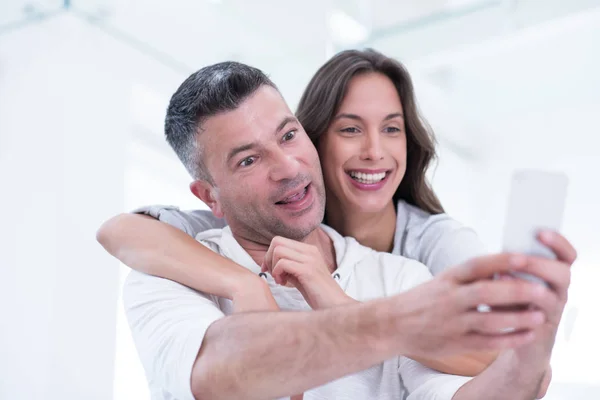 Casal feliz usando telefone celular em casa — Fotografia de Stock