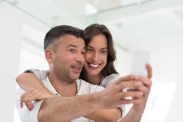 Ευτυχισμένο ζευγάρι που χρησιμοποιεί το κινητό τηλέφωνο στο σπίτι — Φωτογραφία Αρχείου