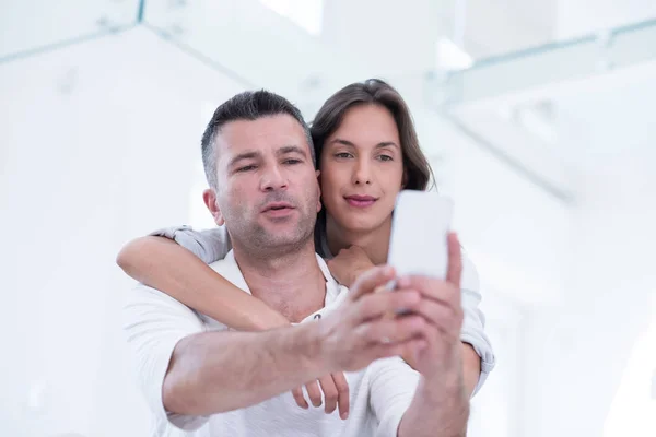 Pareja feliz usando el teléfono móvil en casa —  Fotos de Stock