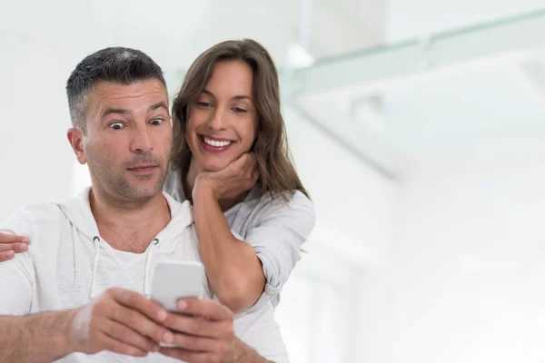 Pareja feliz usando el teléfono móvil en casa —  Fotos de Stock