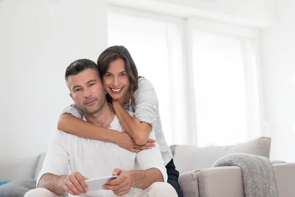 Glada par som använder mobiltelefon hemma — Stockfoto