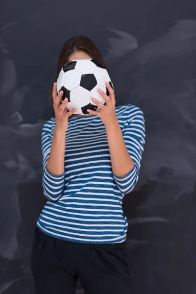 Mujer sosteniendo una pelota de fútbol delante de la pizarra de dibujo — Foto de Stock