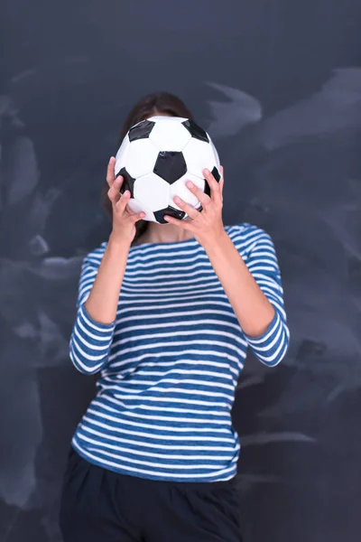 Mujer sosteniendo una pelota de fútbol delante de la pizarra de dibujo — Foto de Stock