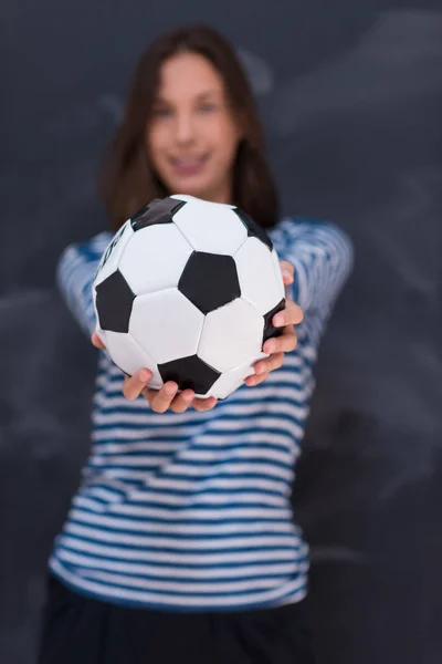 Mulher segurando uma bola de futebol na frente do quadro de desenho de giz — Fotografia de Stock