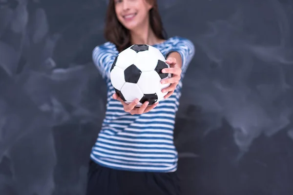 Mulher segurando uma bola de futebol na frente do quadro de desenho de giz — Fotografia de Stock