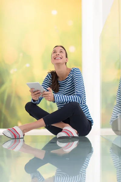 Jonge vrouw met behulp van tablet pc op de verdieping — Stockfoto