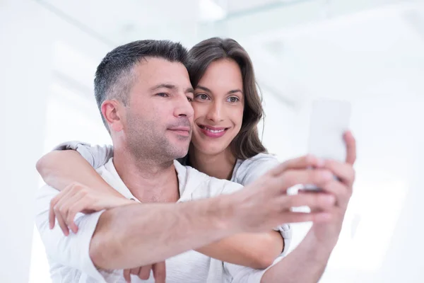 Happy couple using mobile phone at home — Stock Photo, Image