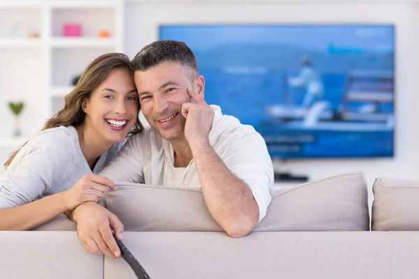 Jovem casal no sofá assistindo televisão — Fotografia de Stock