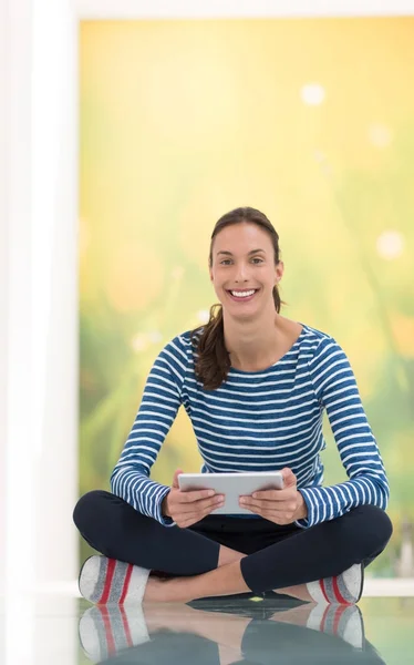 Jonge vrouw met behulp van tablet pc op de verdieping — Stockfoto