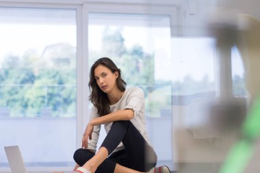 yere dizüstü bilgisayar kullanan genç kadın