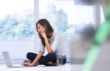yere dizüstü bilgisayar kullanan genç kadın