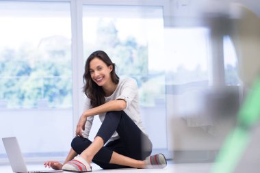 yere dizüstü bilgisayar kullanan genç kadın
