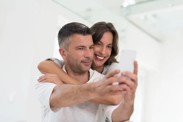 Happy couple using mobile phone at home — Stock Photo, Image