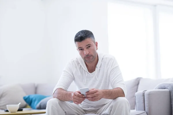 Jonge man met behulp van een mobiele telefoon thuis — Stockfoto