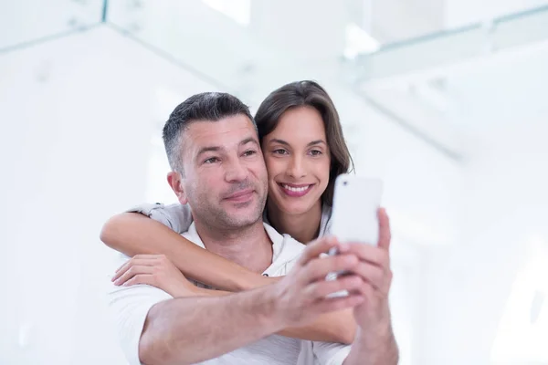 Happy couple using mobile phone at home — Stock Photo, Image