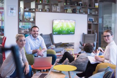 Bir grup genç iş adamı modern ofis binasında iş planlarını tartışıyor