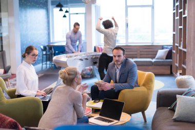 Bir grup genç iş adamı modern ofis binasında iş planlarını tartışıyor