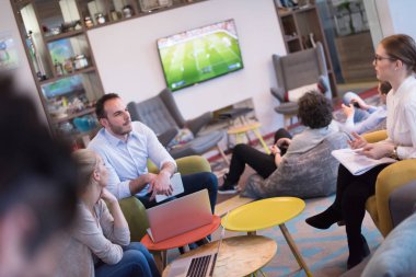 Bir grup genç iş adamı modern ofis binasında iş planlarını tartışıyor