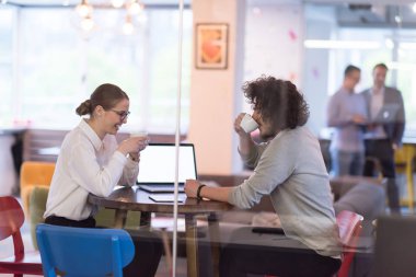 Bir sonraki toplantı için dizüstü bilgisayar kullanan girişimciler kahve içerken ve yaratıcı ofiste fikirleri tartışırken...