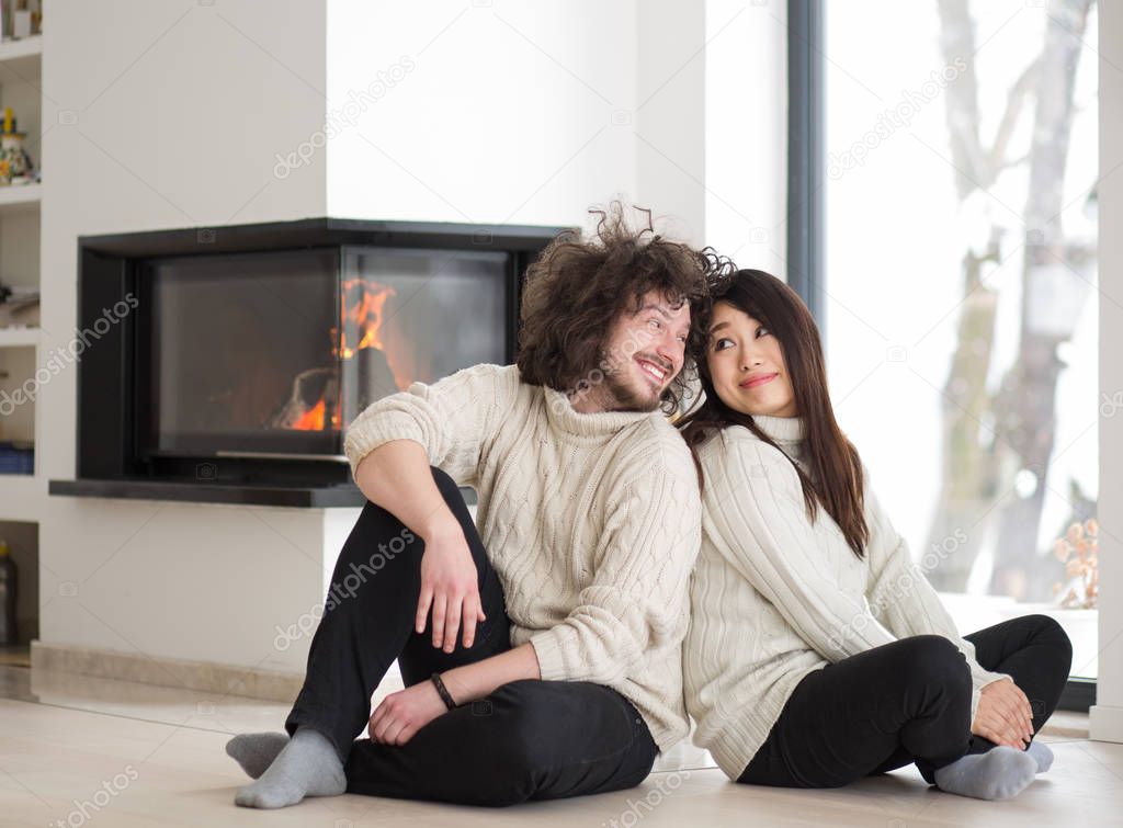 happy multiethnic couple  in front of fireplace