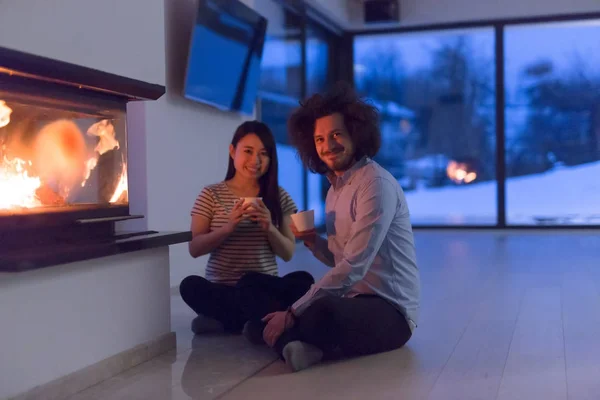 暖炉の前に座って幸せな民族カップル — ストック写真