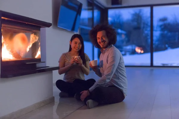 Feliz pareja multiétnica sentada frente a la chimenea —  Fotos de Stock