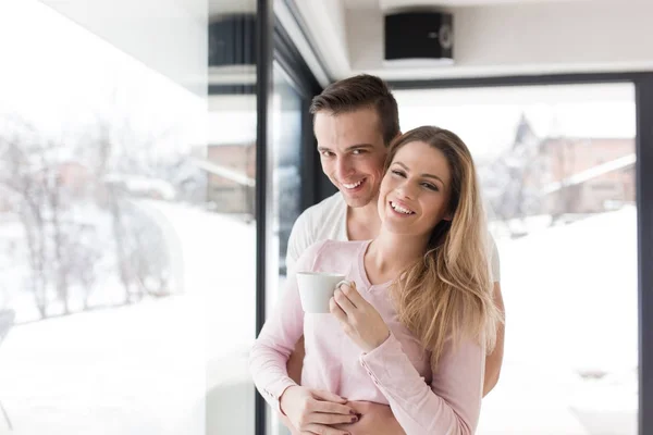 Jong koppel genieten van's ochtends koffie bij het raam — Stockfoto