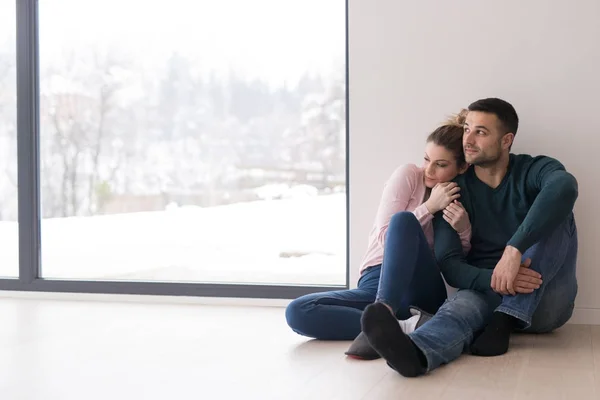 Jovem casal sentado no chão perto da janela em casa — Fotografia de Stock