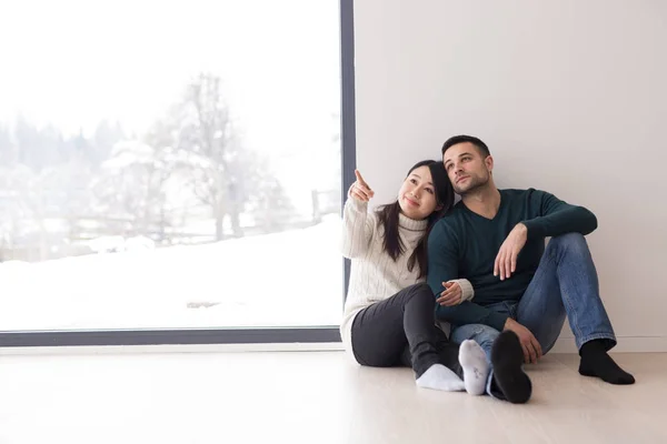 Casal multiétnico sentado no chão perto da janela em casa — Fotografia de Stock