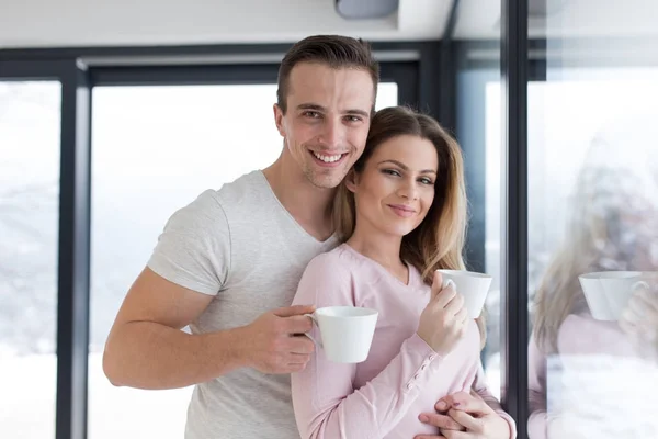 Jong koppel genieten van's ochtends koffie bij het raam — Stockfoto