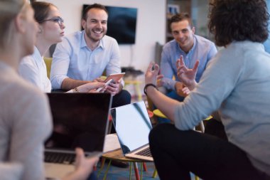 Bir grup genç iş adamı modern ofis binasında iş planlarını tartışıyor