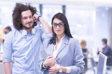 İş adamları, arka planda iş arkadaşlarıyla buluşmaya hazırlanırken tablet bilgisayarı kullanıyorlar ve başlangıç ofisinde fikirleri tartışıyorlar.