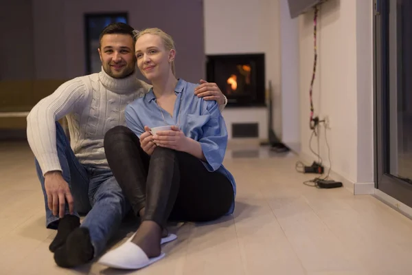 Paar sitzt auf dem Boden vor Kamin — Stockfoto