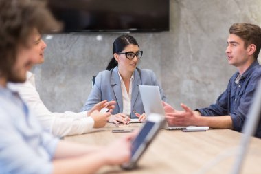 Bir grup genç iş adamı modern ofis binasında iş planlarını tartışıyor