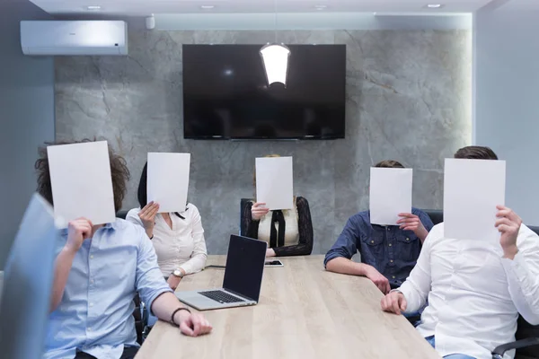スタート アップ オフィスで自分の顔に白い紙を保持若いビジネス チームの肖像画 — ストック写真