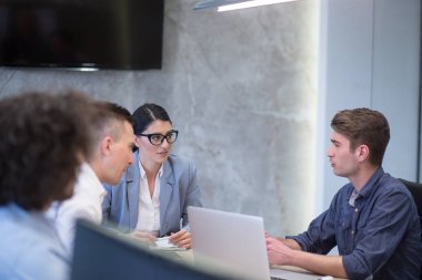 Bir grup genç iş adamı modern ofis binasında iş planlarını tartışıyor