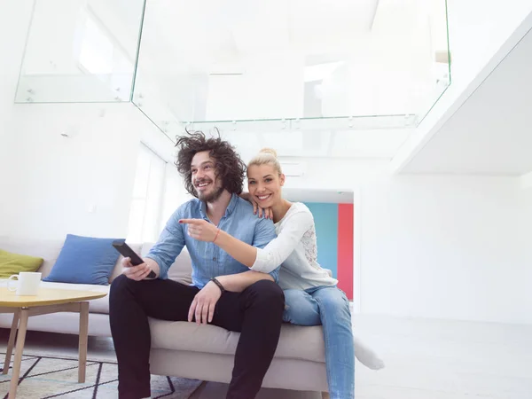 Pareja joven en el sofá viendo la televisión —  Fotos de Stock