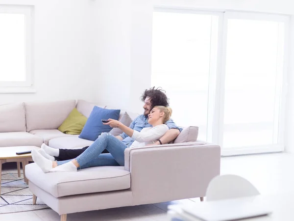 Jeune couple sur canapé regarder la télévision — Photo