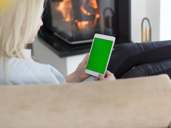 Mujer joven usando tableta frente a la chimenea — Foto de Stock