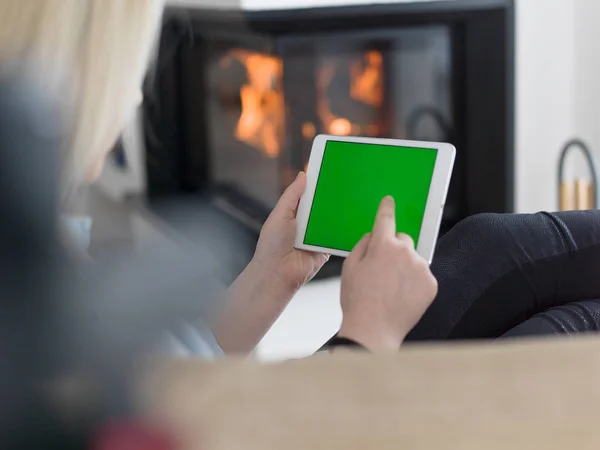 Mujer joven usando tableta frente a la chimenea —  Fotos de Stock