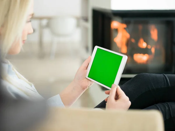 Mujer joven usando tableta frente a la chimenea —  Fotos de Stock