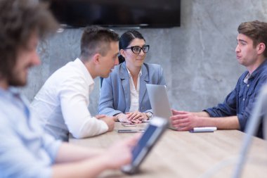 Bir grup genç iş adamı modern ofis binasında iş planlarını tartışıyor