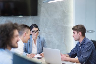 Bir grup genç iş adamı modern ofis binasında iş planlarını tartışıyor