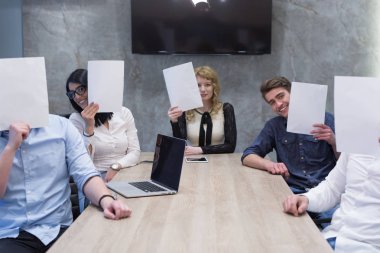 başlangıç iş ekibi beyaz bir kağıt yüz üzerinde tutarak