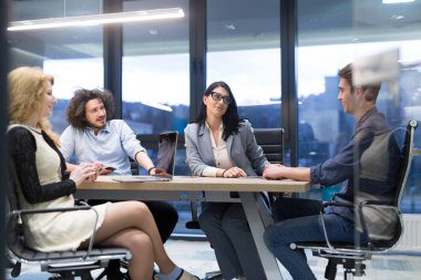 Bir grup genç iş adamı modern ofis binasında iş planlarını tartışıyor