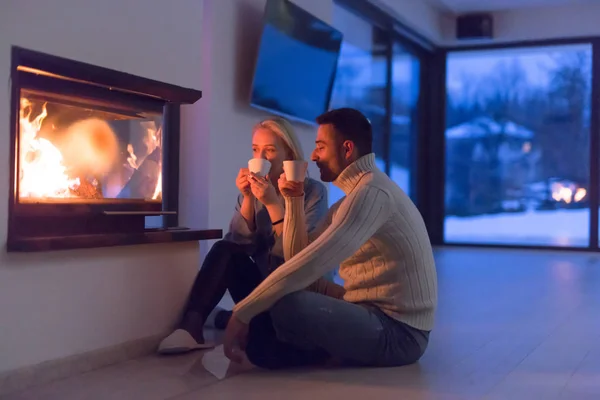 Paret sitter på golvet framför öppen spis — Stockfoto